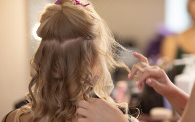 Fototapeta premium Master hairdresser makes hair style girl with hairdryer and hair care products