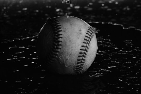 Old used baseball in water for moody sports background.