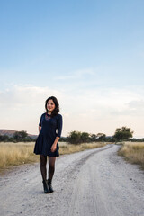 Young adult Mexican woman standing in a dirt road looking at the camera