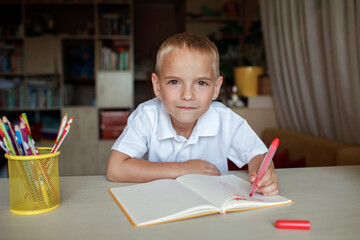 Happy left-handed boy writing in the paper book with his left hand, international left-hander day celebration, only lefties understand
