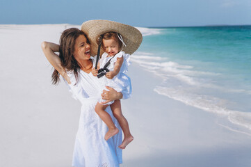 Young mother with her little daughter at the beach by the ocean