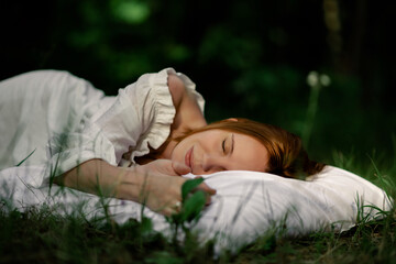 Healthy sound sleep. Rest, relaxation in the forest. Woman sleeps on a pillow on a green glade in the forest.