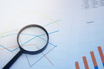 Magnifying glass on charts, graphs and financial statements. Inventory chart analysis and financial accounting. Copy space. Can be used for presentations