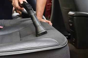 Man vacuum cleaning his car seats interior