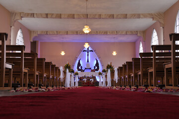 Church altar decorated for a wedding surrounded by chairs and lights