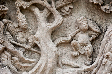 stone panel depicting a mythological dancing man and a warrior in armor with a spear