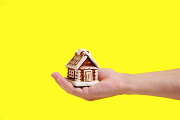 Toy house on palm of your hand on yellow background, mortgage sale or purchase of real estate, houses, apartments.