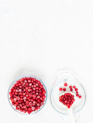 Frozen cranberries in a bowl on a white background. Frozen red berries. Vertical orientation. Copy space, top view, flat lay.