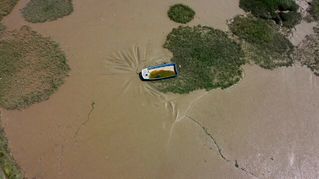 4K drone video over wet sand banks with a single rotting boat
