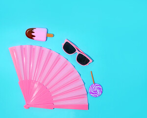 Women's accessories. Pink fan, glasses and ice cream on a summer blue background.