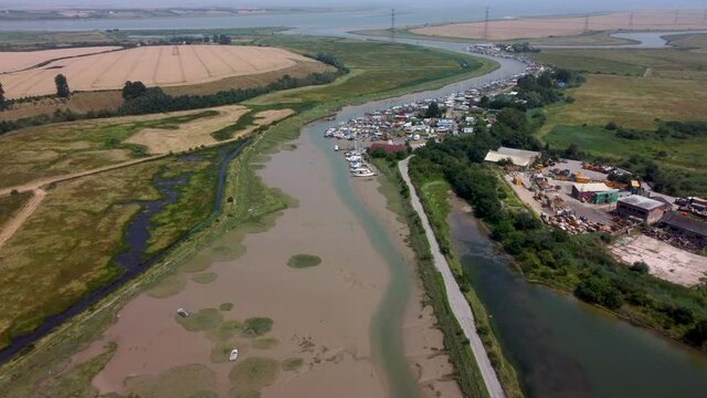 4K drone footage over a creek towards boats in low tide