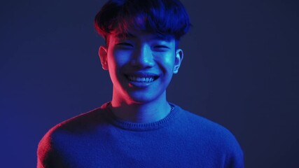 Happy people. Neon light face. Positive attitude. Good mood. Red blue color glow satisfied pleased joyful smiling Asian guy isolated on dark background.