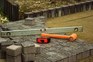 Budowa chodnika - młotek, poziomica i metrówka . Construction of the pavement - a hammer, a spirit level and a ruler. 