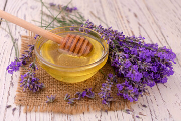 Obraz na płótnie Canvas Bowl with fresh lavender honey on a white wooden background.