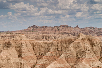 Badlands National Park, SD, USA - June 1, 2008: Wide landscape filled by beige mountains and heavy blue cloudscape. Colored lines run horizontally through entire range.