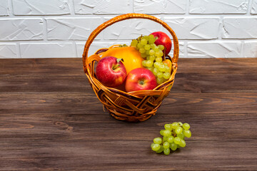 Grapes and apples in a wicker basket on a wooden table. Harvest concept. Place for an inscription.