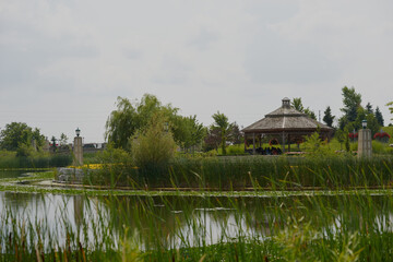 Beautiful colorful summer spring natural landscape with a lake in Park surrounded by green foliage of trees in sunlight and stone path in foreground.