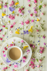 Obraz na płótnie Canvas Сup of coffee with milk on a wooden background with small flowers, good morning, top view 
