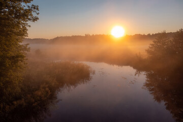 Fototapeta na wymiar Beautiful small river covered with fog in the morning. Rural landscape at sunrise