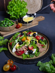 Tuna salad in a ceramic plate according to the French recipe on a dark wooden background