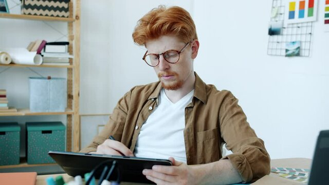 Portrait of young man designer working with tablet computer drawing drafting indoors at home