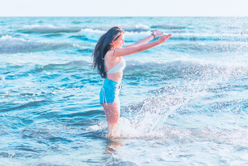 Young woman playing in the sea.woman make in sea water splash.Cheerful young woman having fun on the summer beach.