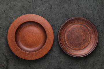 Two Rustic Plates on gray background. Empty brown clay plate on black stone table. Top view with copy space. Rustic dishes