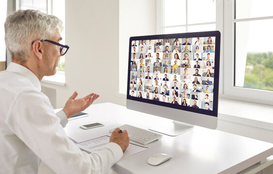 Businessman Meeting Whole Crowd Of Senior And Young International Online Colleagues And Looking At Many Happy Faces On Computer Screen During Modern Virtual Global Video Conference Or Business Webinar