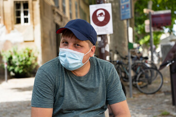 A man in a medical mask and a baseball cap against the background of a sign on the mandatory...