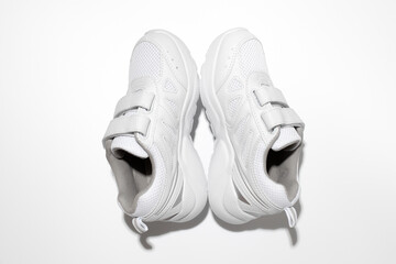 minimalistic flat lay white sneakers for women standing in the form of a pyramid or tent isolated on a white background.