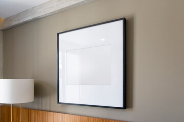 Modern house decoration, empty black square frame, poster, white canvas, mock up, on a gray wall, ...