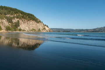 Cliffs and beach seen at Doctors Point, Dunedin, New Zealand