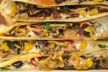 Beautiful closeup detailed view of delicious creamy black bean Mexican quesadillas with sweet corn, avocado, red onion, chili pepper and coriander on wooden serving board. Quesadilla background