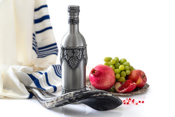 Talit, bottle of wine, shofar, vintage plate with pomegranate, apple and grapes. Rosh hashanah