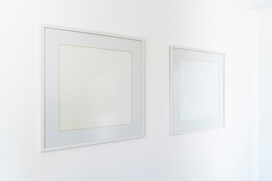 Empty square white frame, poster white canvas mock up on a white wall, living room, template angle view gallery, home decoration