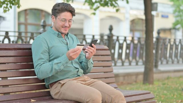 Man making Online Payment on Smartphone in Park Bench 