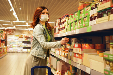 Pretty woman choosing groceries at supermarket. Female consumer purchasing goods at mall, walking among shelves. Girl with mask shopping of food