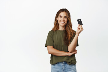 Image of smiling woman easy paying contactless, showing credit card and looking carefree, buying...
