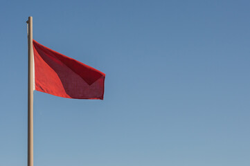 a flag of red on the beach that forbids swimming