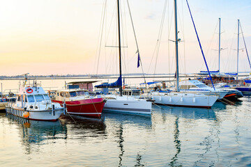 Fototapeta premium Sports private yachts are moored at the yacht club against the backdrop of the evening sky and sunset.