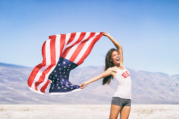 USA flag happy American Asian sports athlete woman waving after game winning cheering at outdoor...