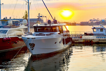 Private yachts are moored at the dock against the backdrop of the evening sky and sunset.