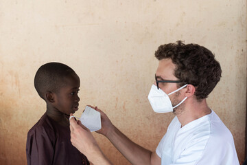 How to put on a mask: African black boy getting instructions from caucasian nurse