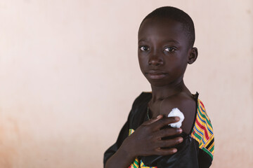 Handsome young African black Boy showing a cotton bandage after getting a vaccine.