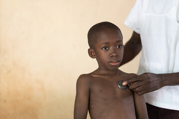 Health symbol: African black doctor with lab coat examining young African child with stethoscope.