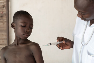 African black doctor ready to vaccinate little African ethnicity boy