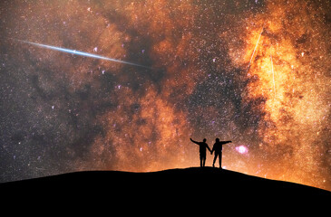 A beautiful starry night, a couple stand on a hill and look at the Milky Way galaxy. Night landscape, astronomical background.