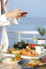 Woman using smartphone to take photos of food before eating in restaurant