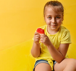 Caucasian little girl with piece of watermelon in her hands on yellow background. Healthy food concept