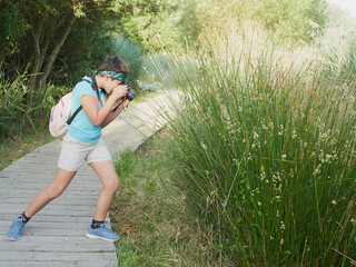Caucasian girl photographing plant during forest excursion